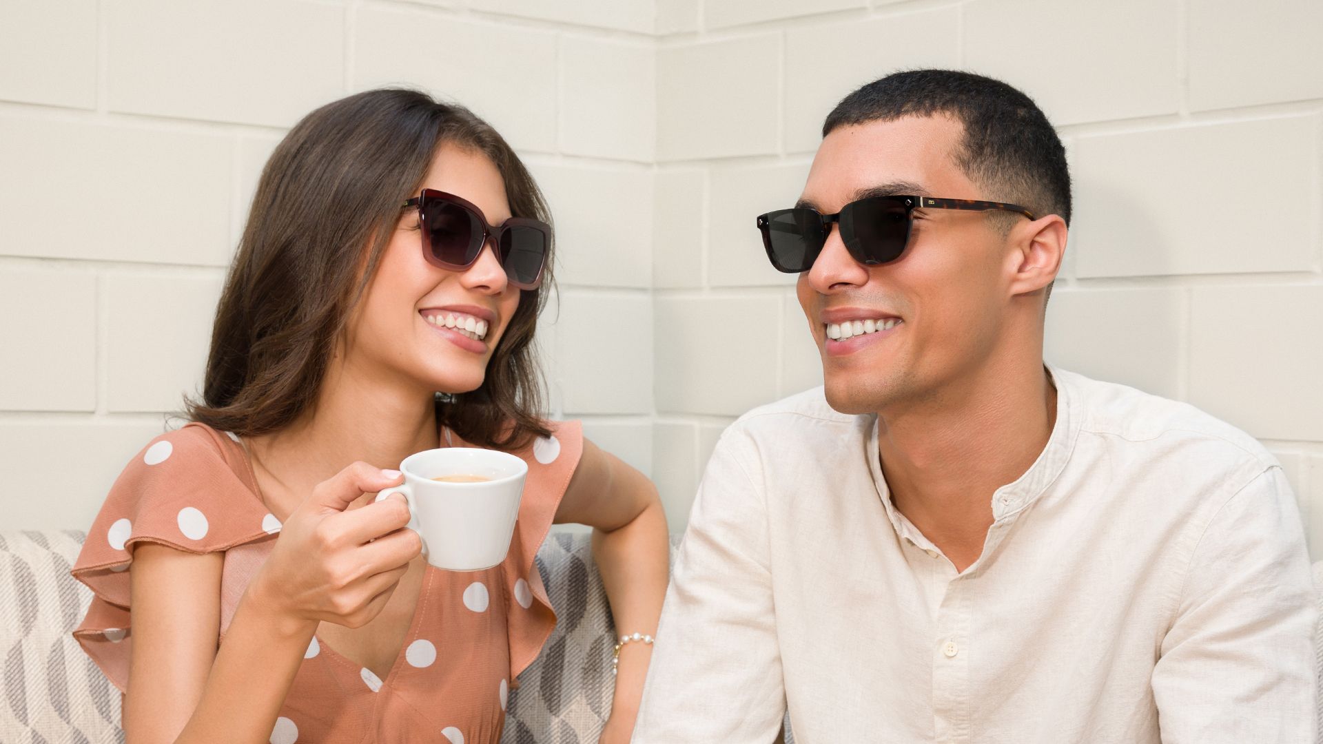 Smiling couple in Biaggi sunglasses sharing a coffee