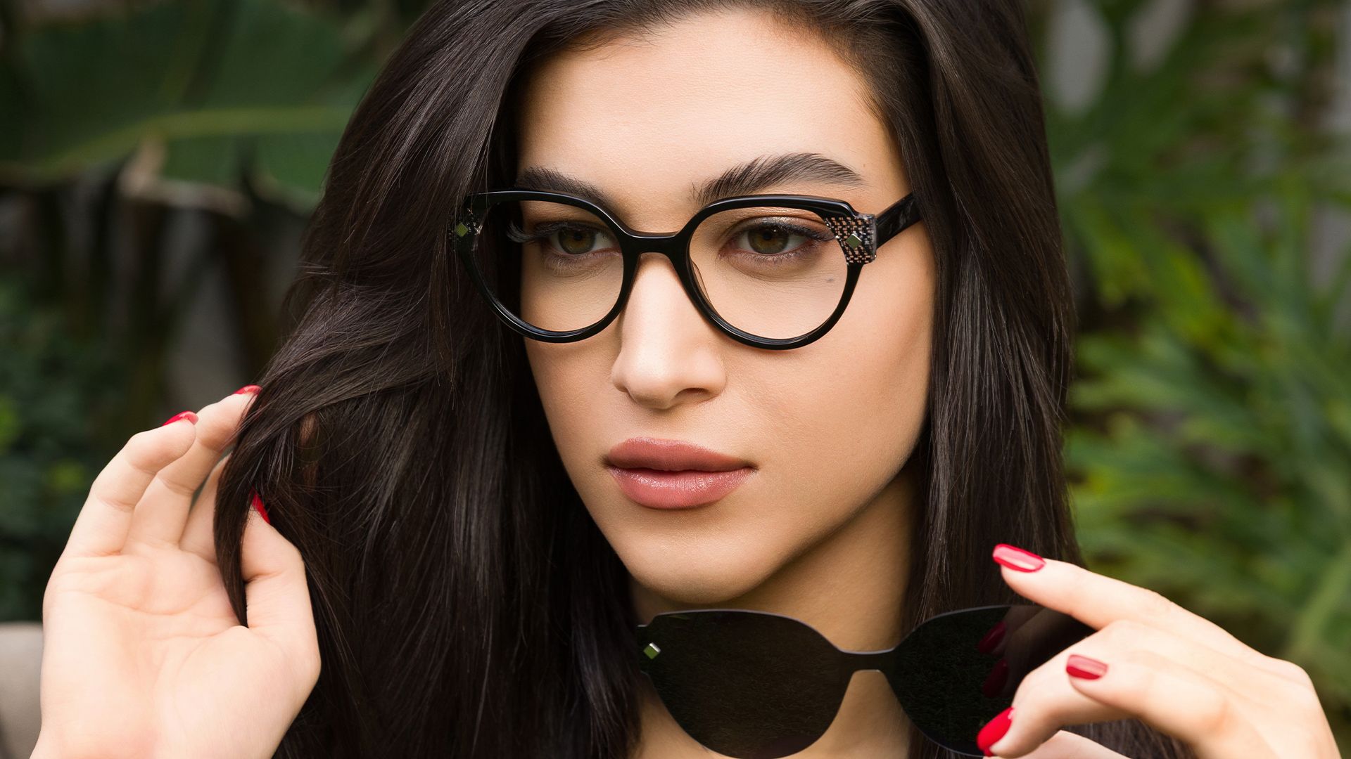 Woman wearing black Biaggi frames, holding the matching clip-on sun lens